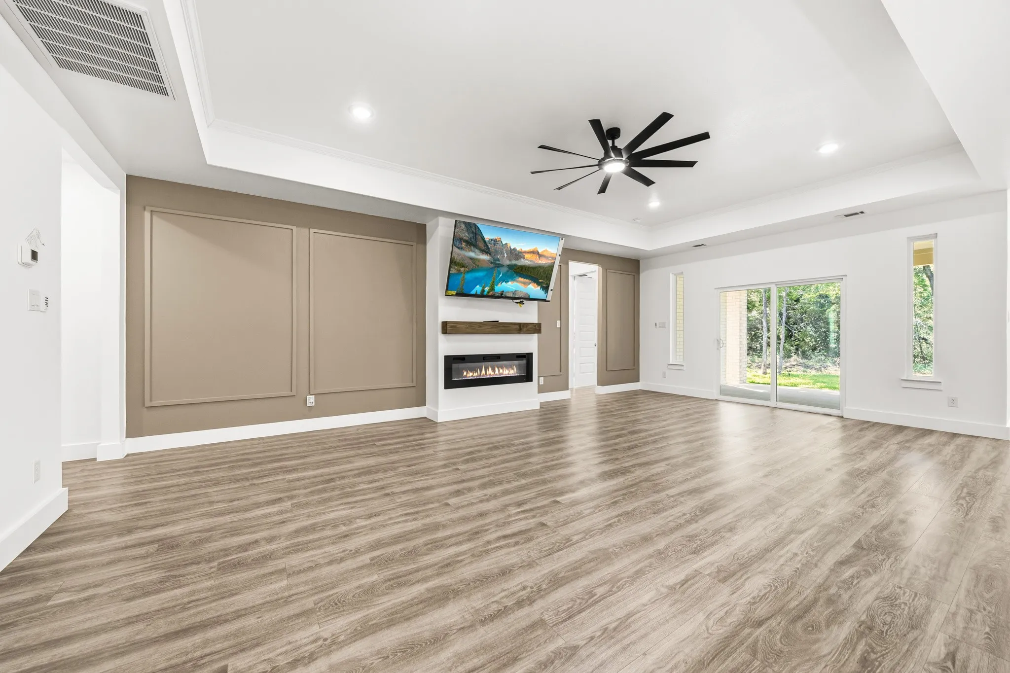 Spacious living area featuring wood-finish flooring, a tray ceiling, and recessed lighting