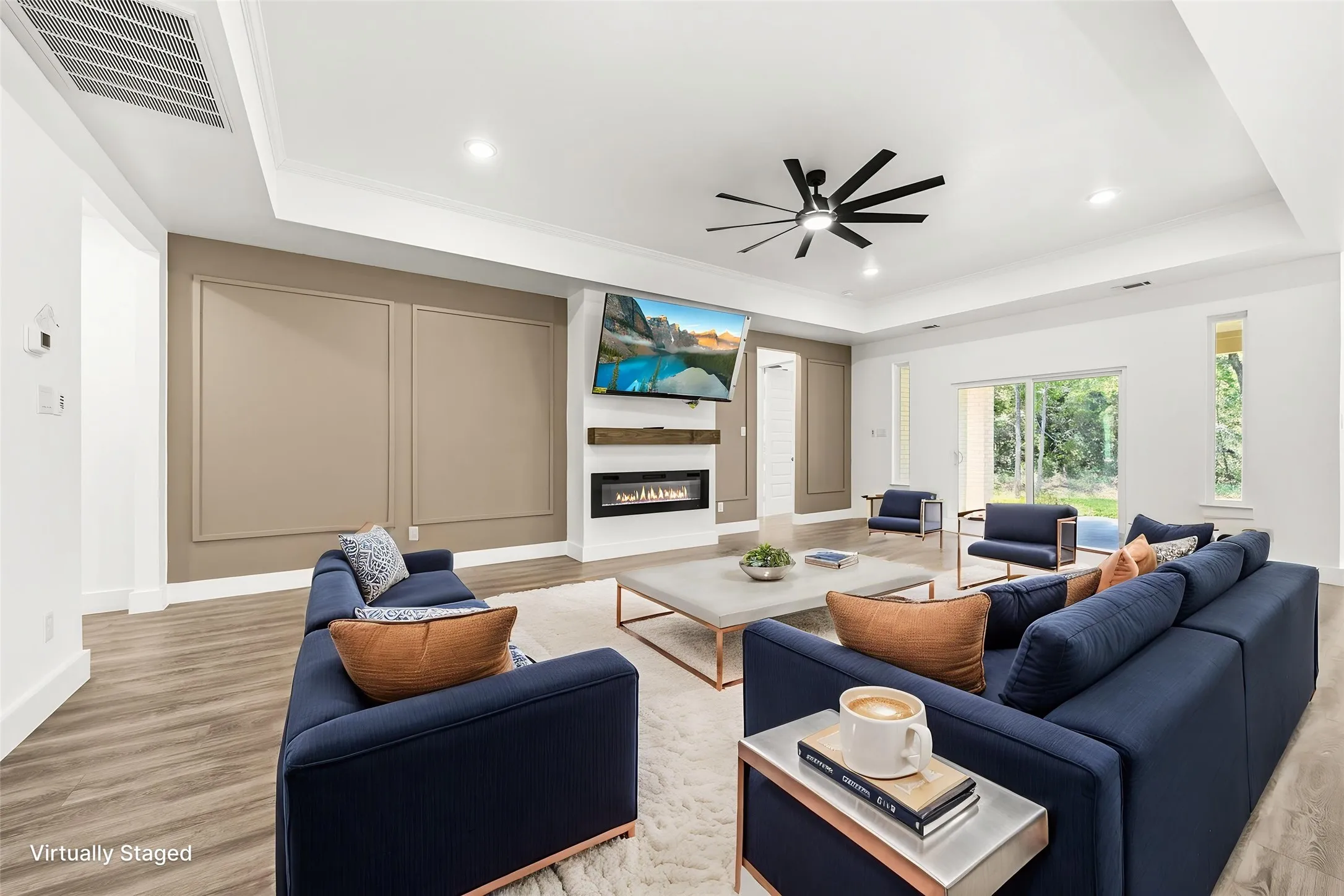 Spacious living area featuring wood-finish flooring, a contemporary ceiling fan, and recessed lighting