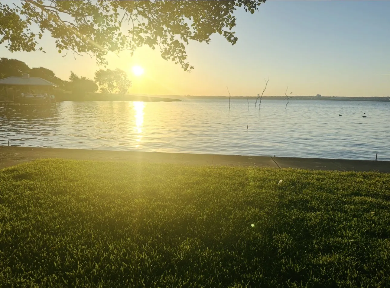 Waterfront property featuring a manicured lawn and a private dock with a covered gazebo