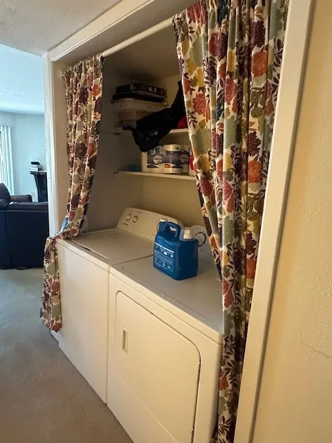 Dedicated laundry area featuring a washer and dryer unit, built-in shelving, and a privacy curtain