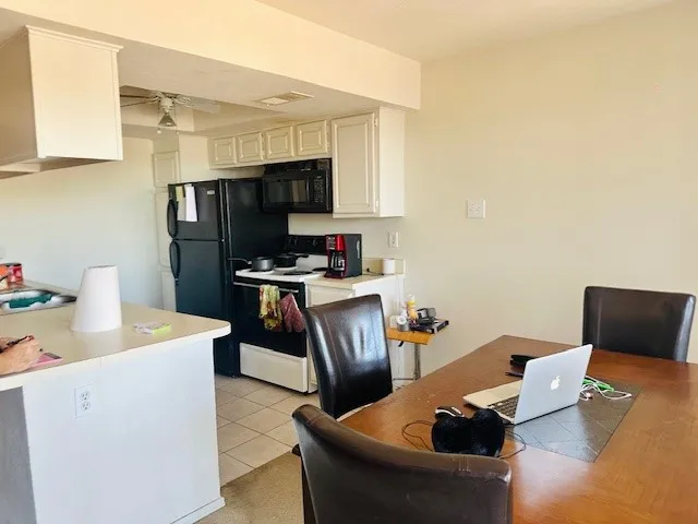 Kitchen featuring white cabinetry, black appliances, a ceiling fan, and tile flooring