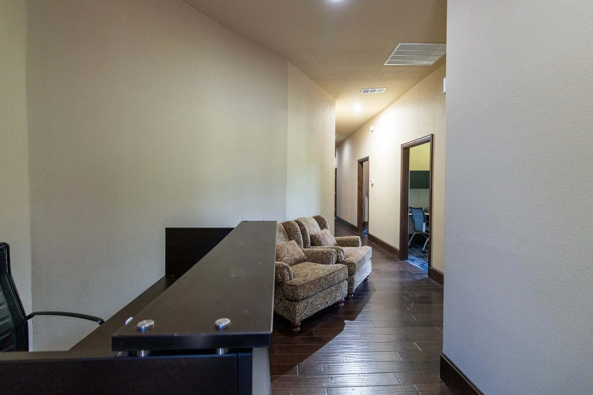 Lobby area featuring wood-finish flooring, recessed lighting, and a dark wood reception desk