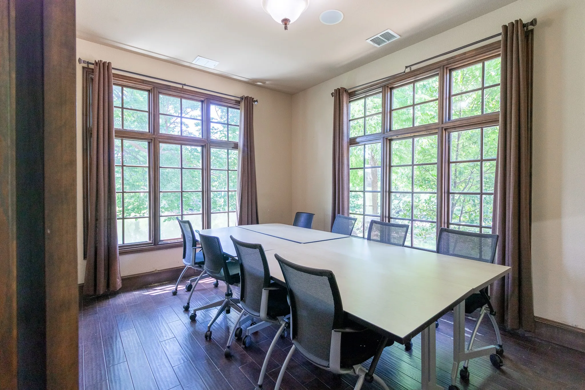 Room featuring expansive windows with grid patterns, dark wood-finish flooring, light-toned walls, and a ceiling-mounted light fixture