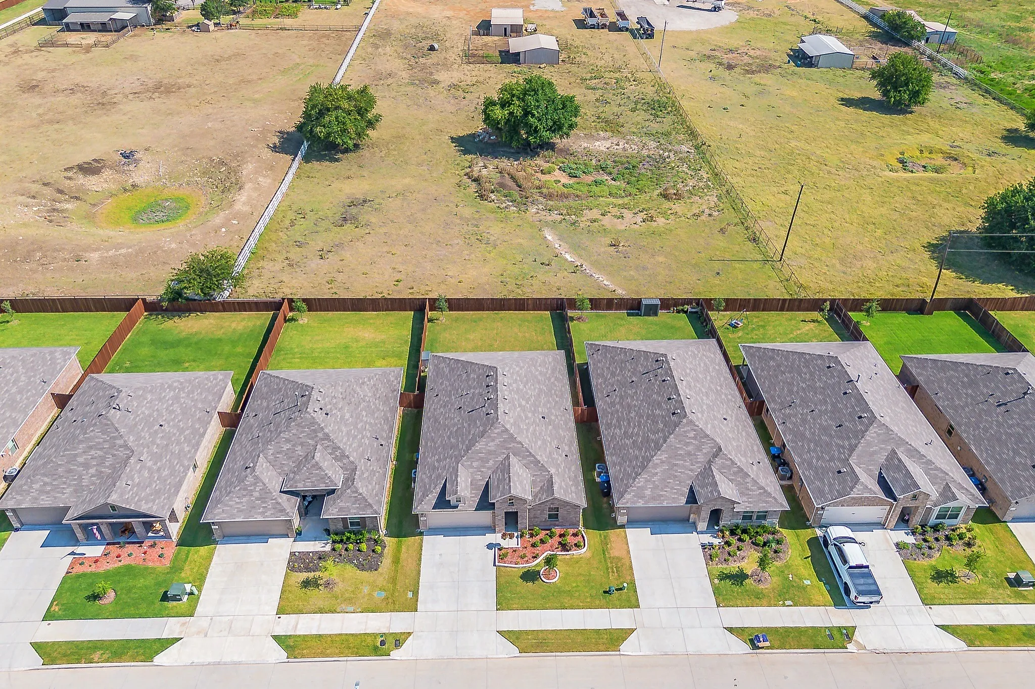 Aerial view showcasing multiple single-story homes with shingle roofs and manicured front lawns