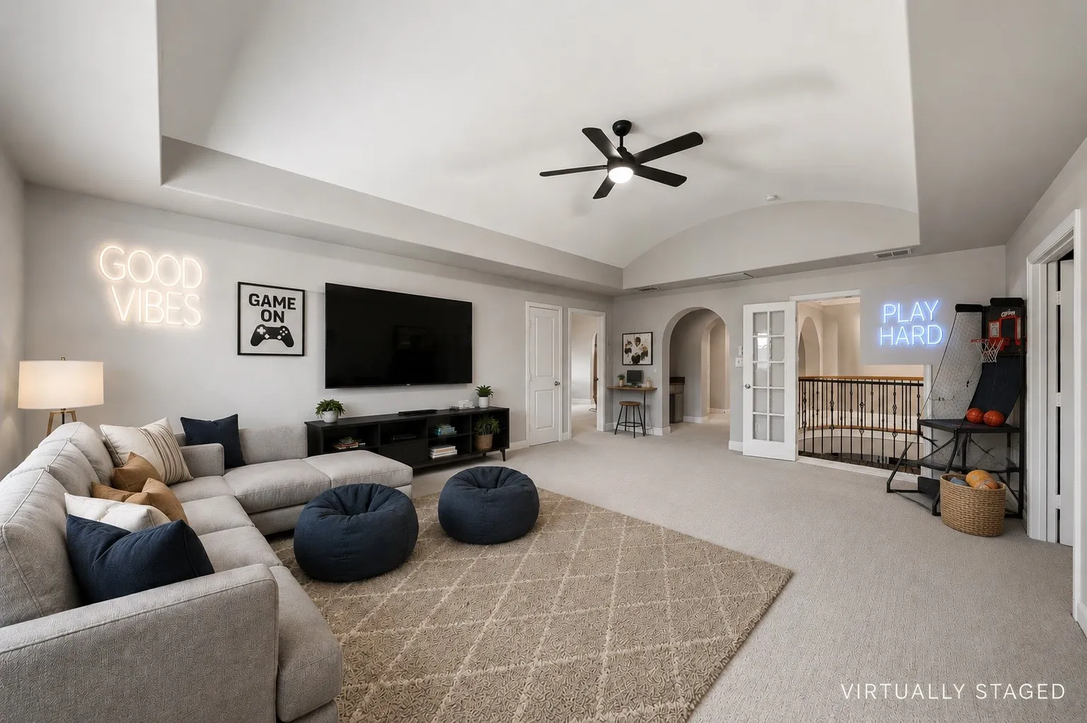 Spacious entertainment room featuring tray ceilings, arched doorways, a ceiling fan, and French doors