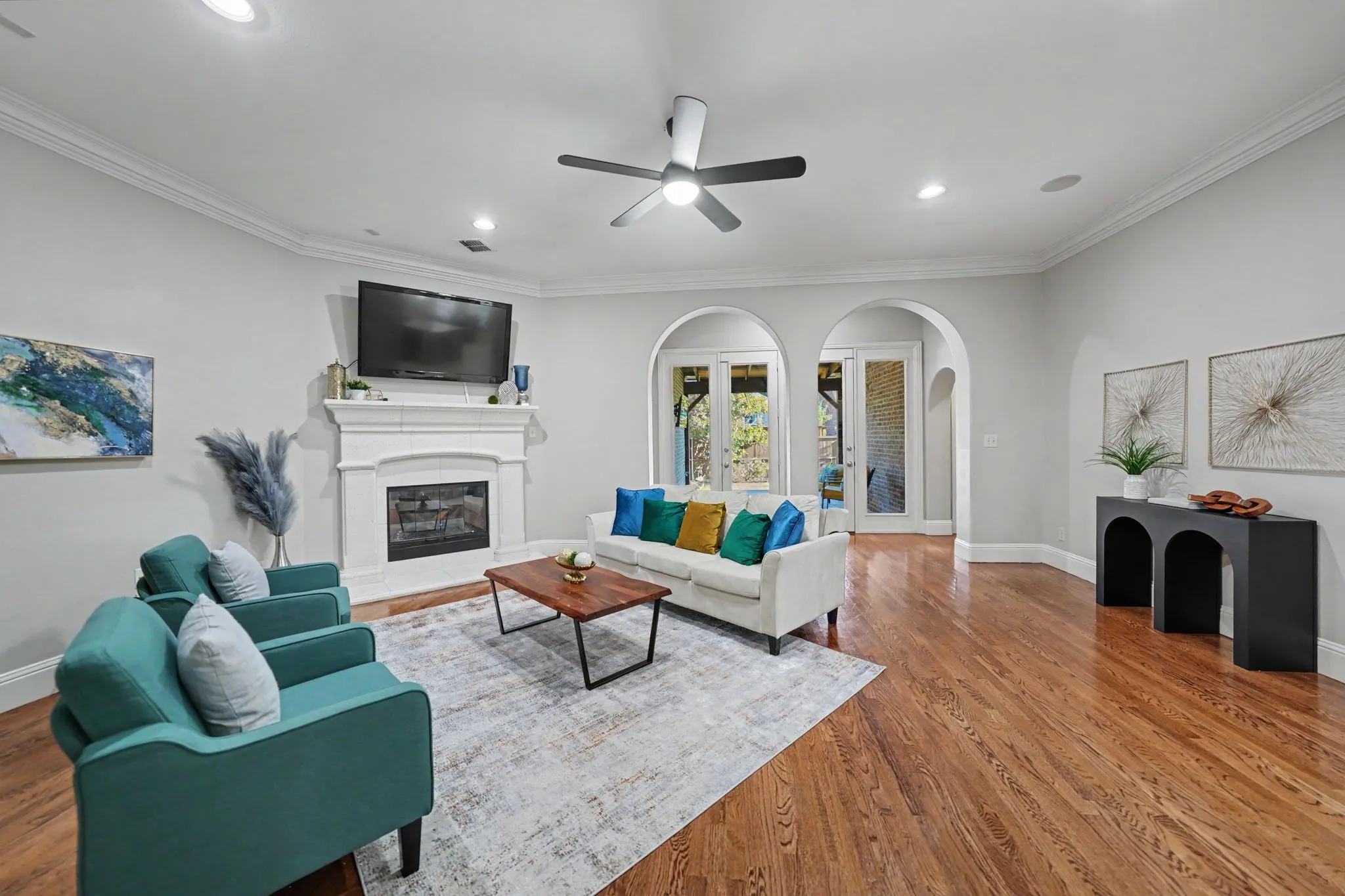 Hardwood flooring, crown molding, white fireplace, recessed lighting, and arched doorways