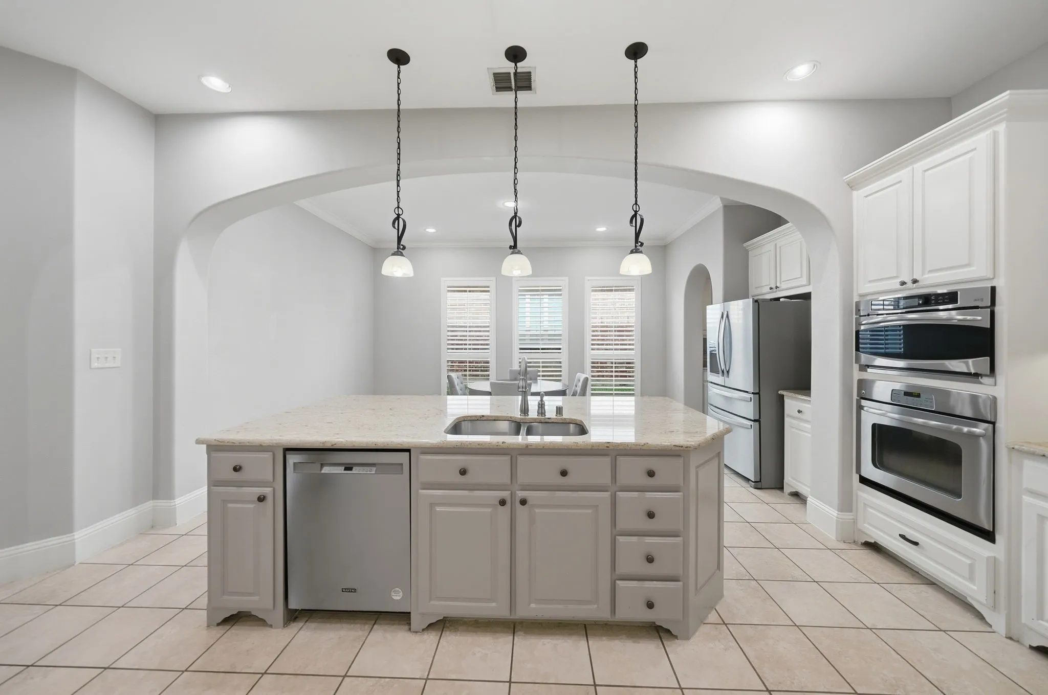 Gourmet kitchen featuring a large central island with an undermount sink, stone countertop, and pendant lighting