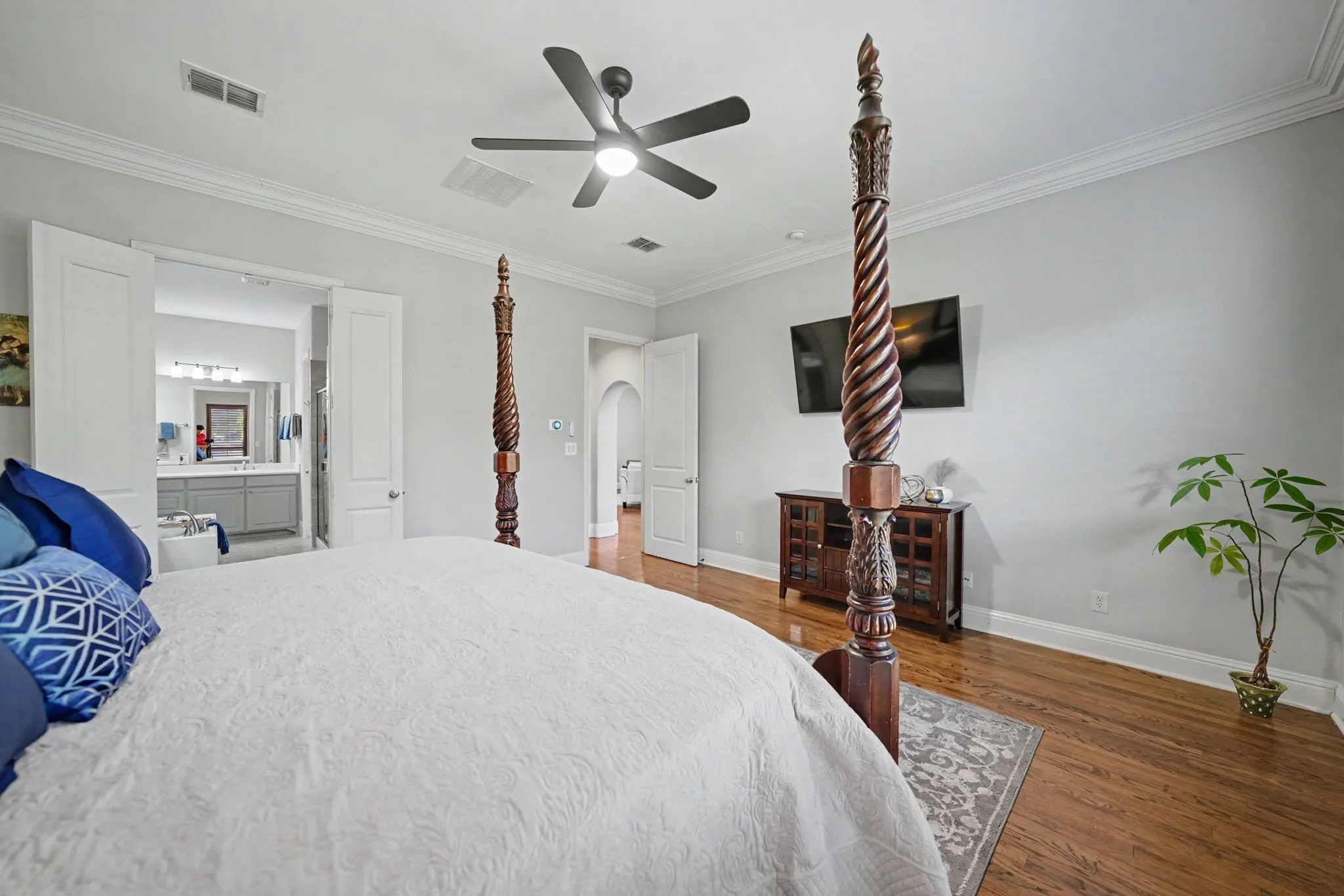 Hardwood flooring, crown molding, ceiling fan with light fixture, and an arched doorway
