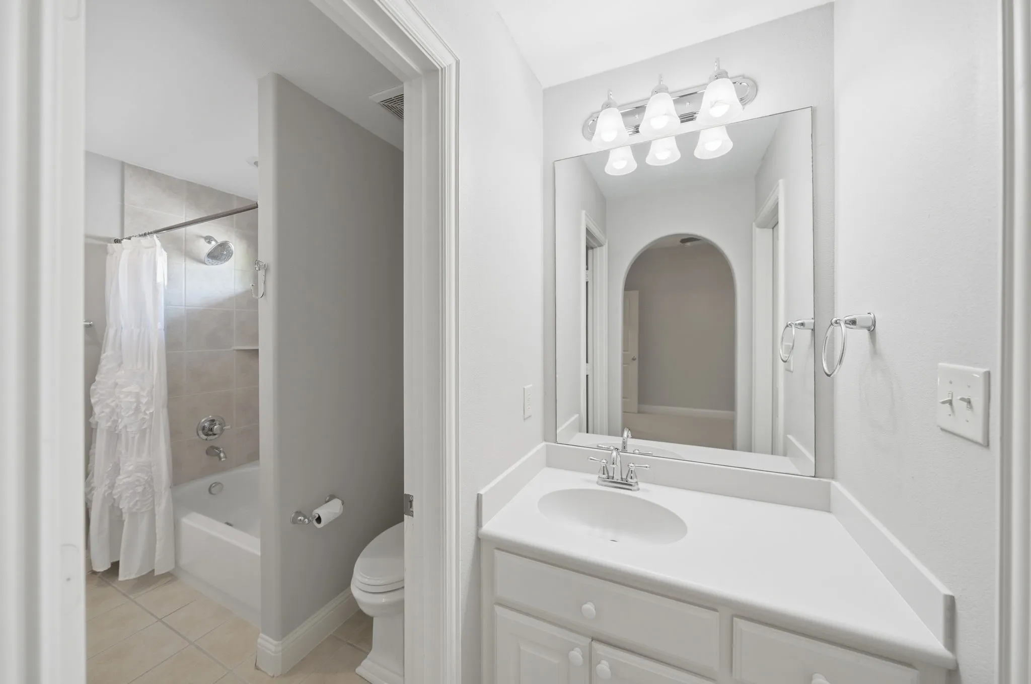 Bathroom vanity with a white countertop and integrated sink, chrome faucet, and a wall-mounted mirror