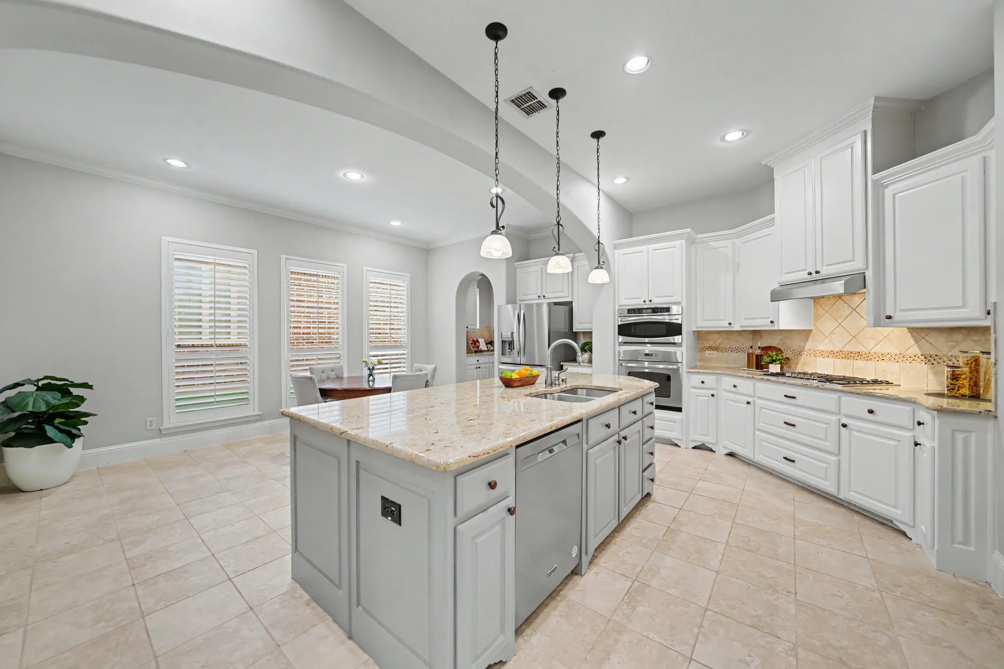 Kitchen featuring a large central island with a sink, white cabinetry, integrated stainless steel appliances, and tile flooring