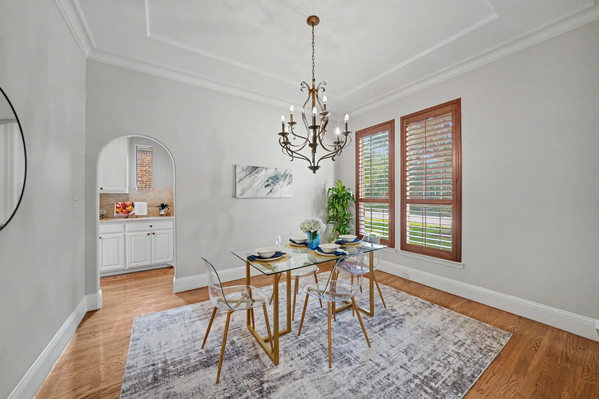 Coffer ceiling with crown molding, hardwood flooring, arched entryway, and two windows with plantation shutters