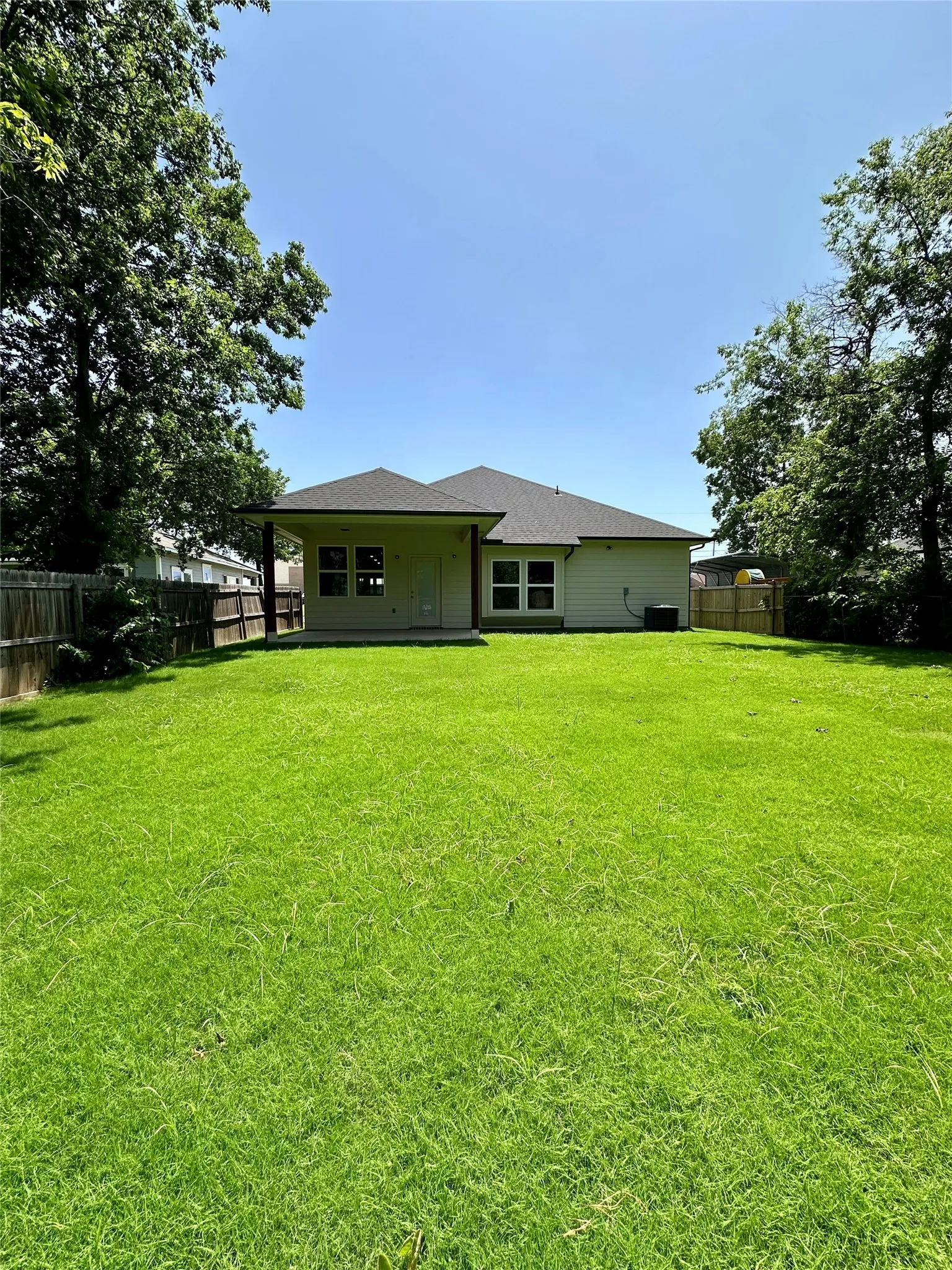 Spacious backyard with a lush green lawn, private fencing, and mature perimeter trees
