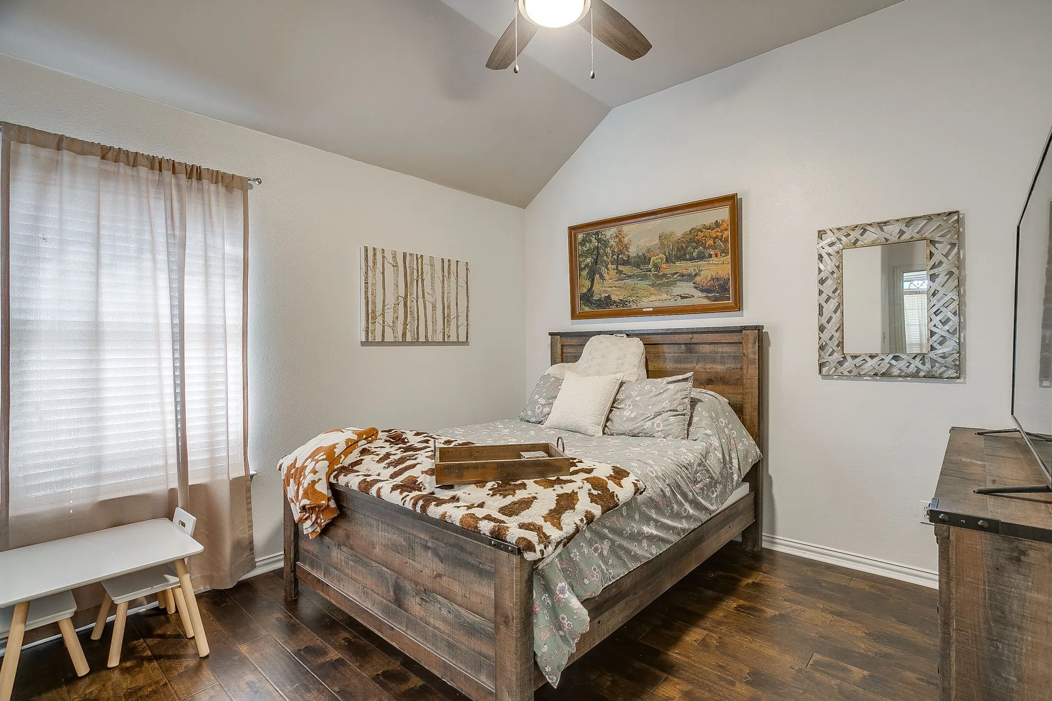 Vaulted ceiling room featuring wood-finish flooring, a window with blinds, a ceiling fan, and white baseboards