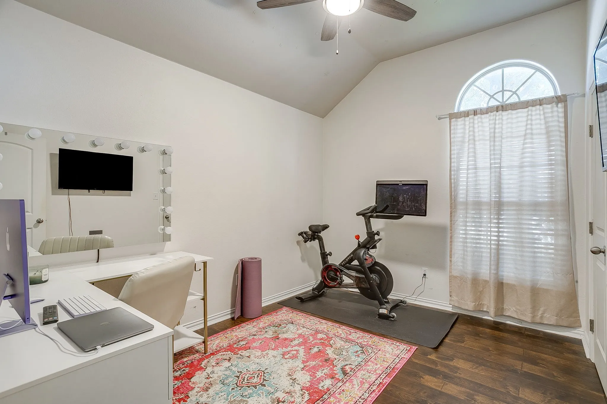 Vaulted ceiling room featuring wood-finish flooring, a ceiling fan, and an arched window with blinds