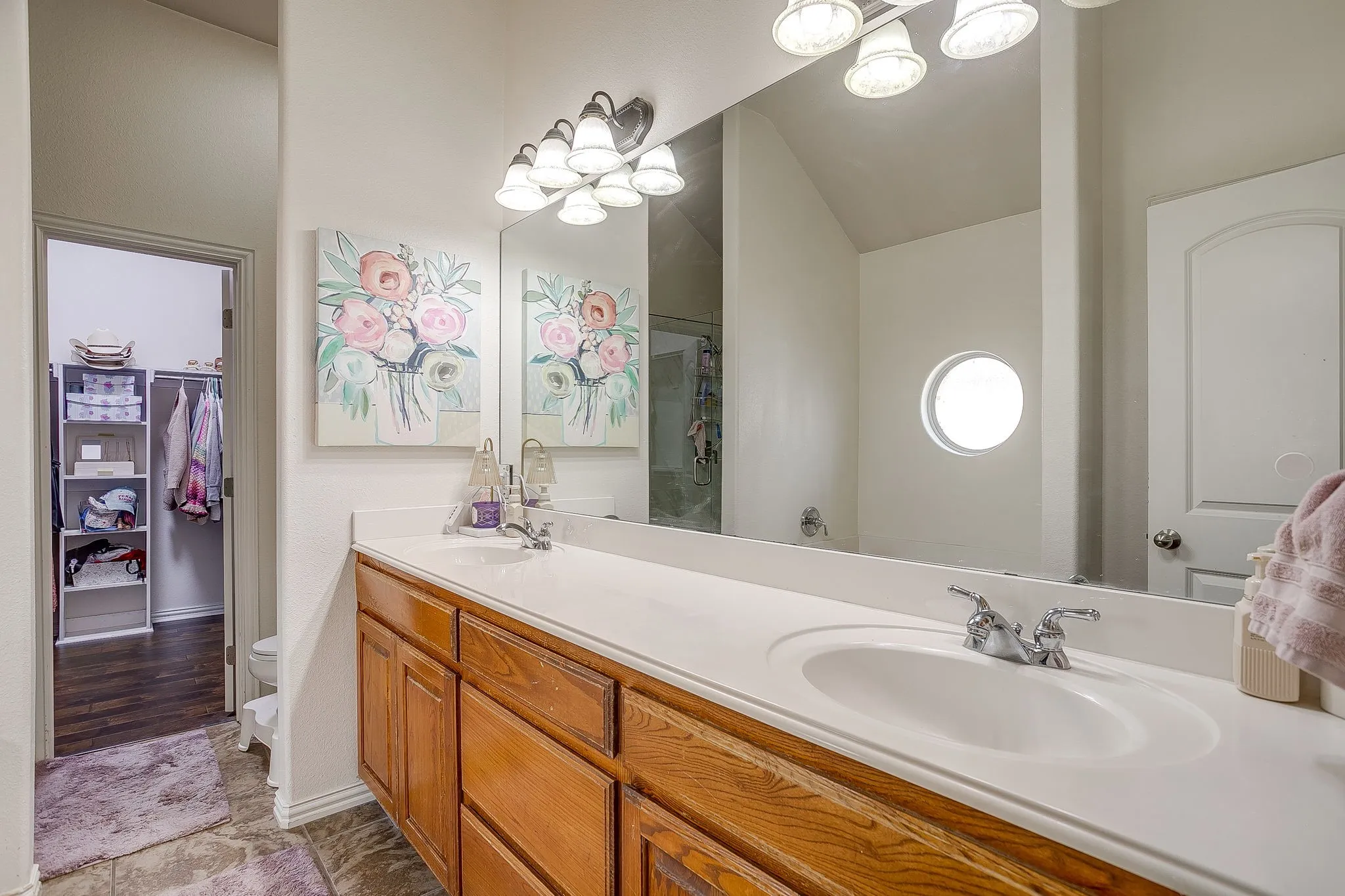 Bathroom vanity featuring dual integrated sinks, chrome faucets, and wood-finish cabinetry
