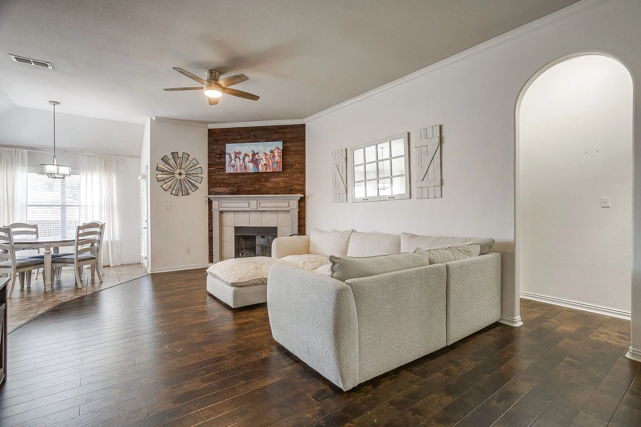 Living area featuring wood-finish flooring, a ceiling fan, and a fireplace with a wood-plank accent wall