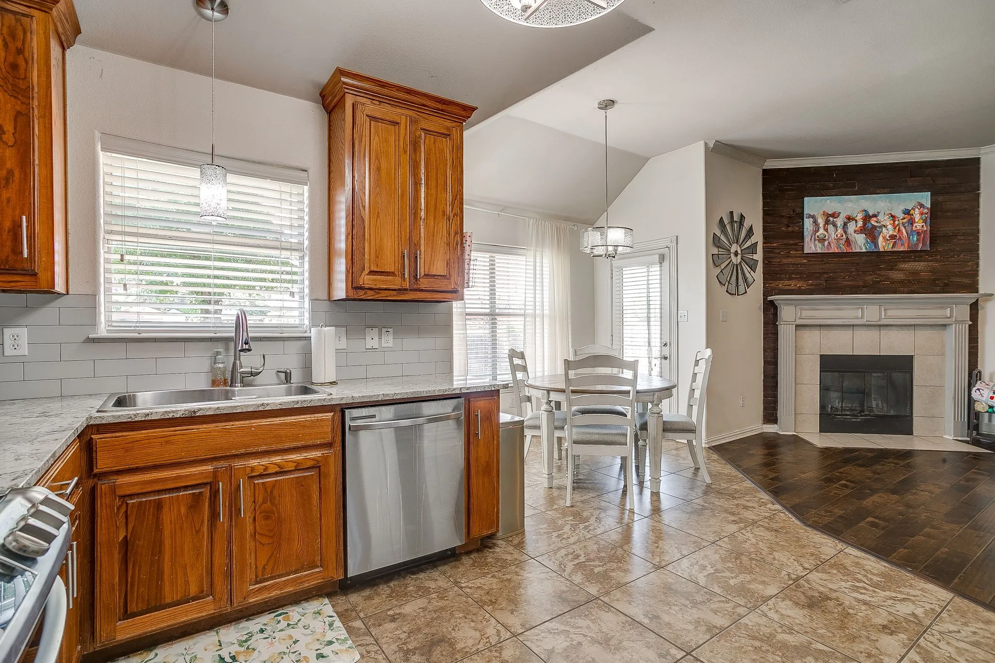 Kitchen featuring wood cabinetry, stainless steel dishwasher, and a double basin sink with an arched faucet