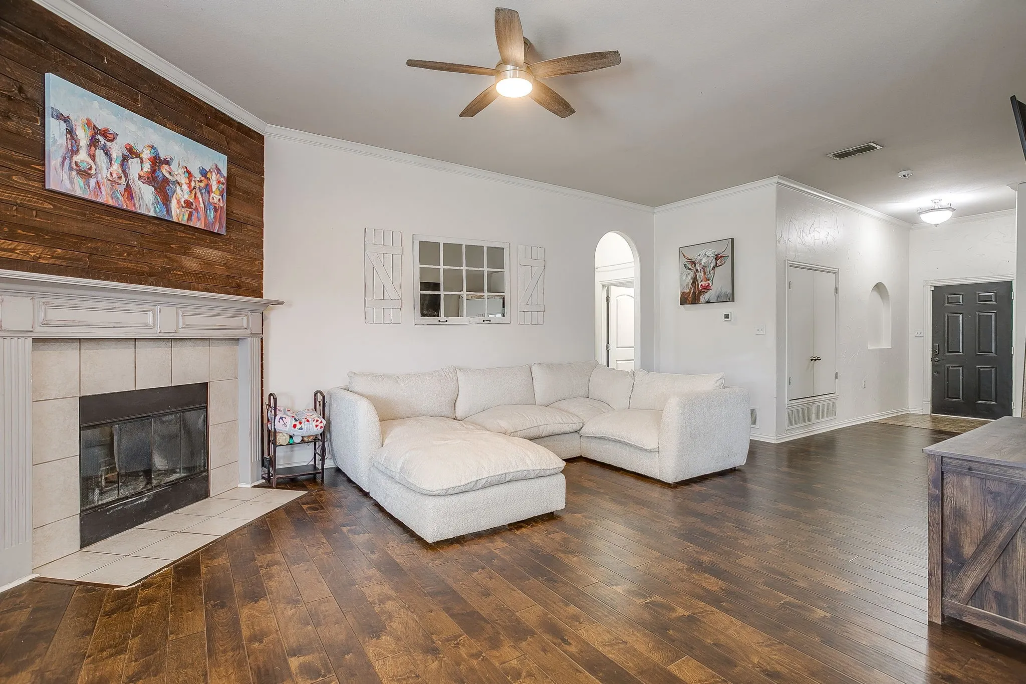Living area featuring wood-finish flooring, a fireplace with a tiled hearth and mantel, and a wood plank accent wall