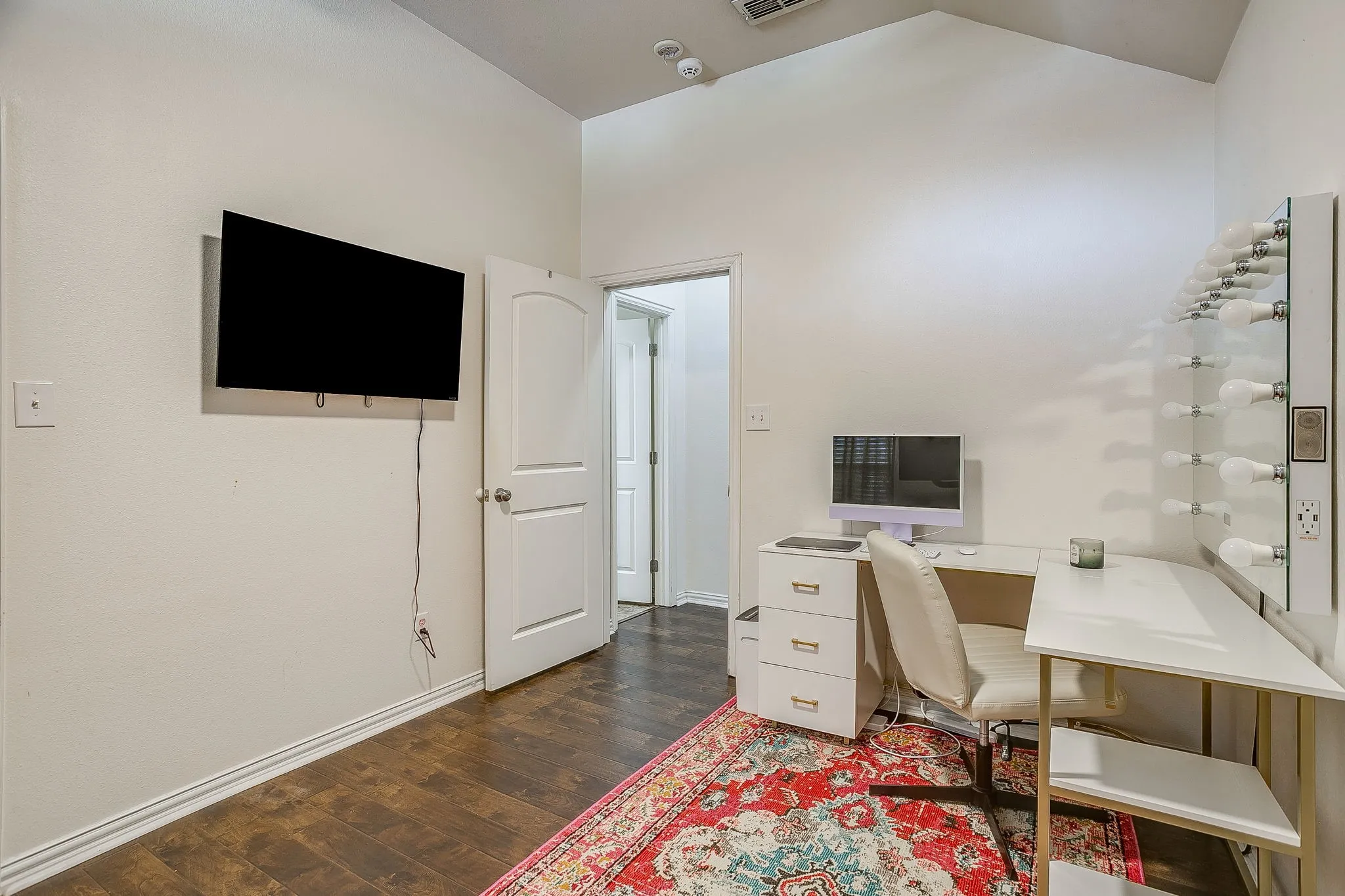Interior space featuring wood-finish flooring, white baseboards, and a vaulted ceiling