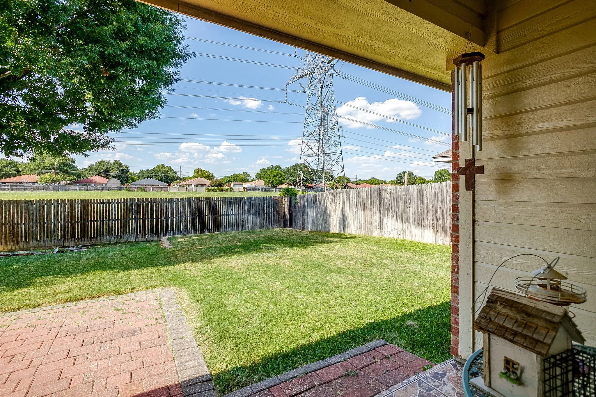Expansive backyard featuring a manicured lawn, a wood privacy fence, and a brick paver patio area