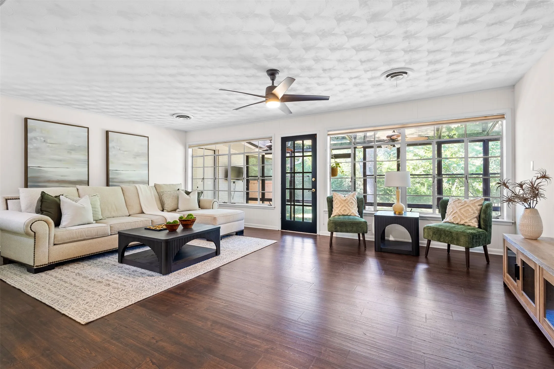 Spacious living area featuring extensive window treatments, wood-finish flooring, and a ceiling fan