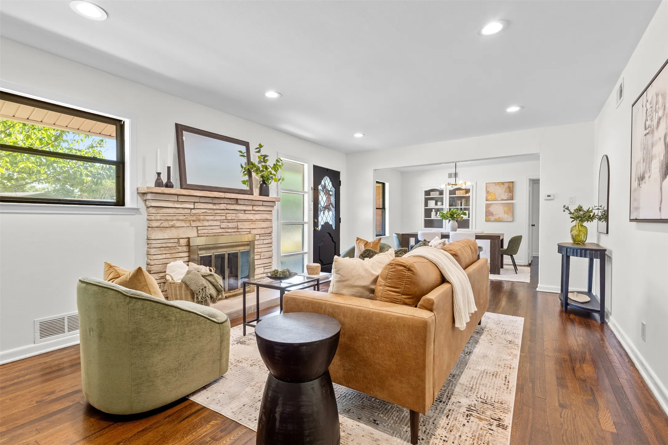 Living area featuring a natural stone fireplace, recessed lighting, wood-finish flooring, and white baseboards