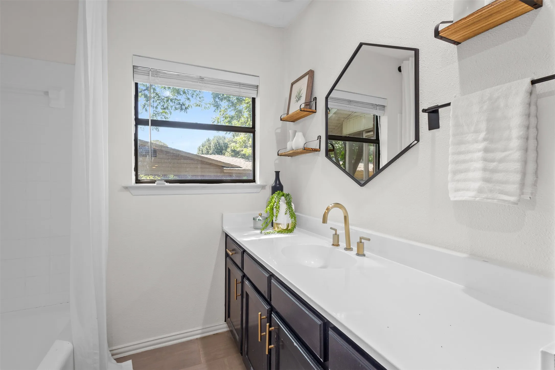 Bathroom vanity featuring a single basin, gold-finish faucet, and white countertop