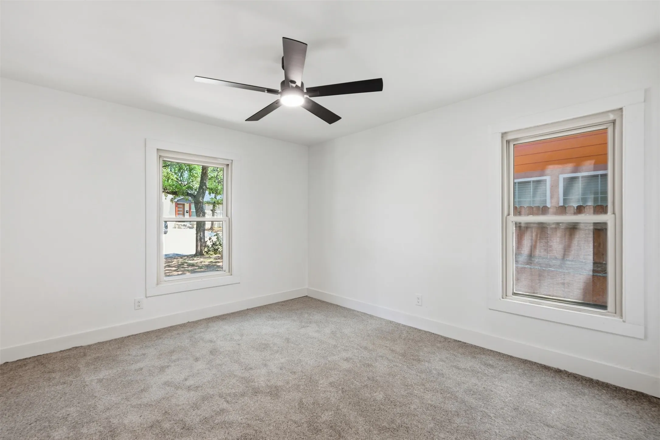 Neutral wall paint with two windows providing natural illumination, complemented by a contemporary ceiling fan with integrated lighting