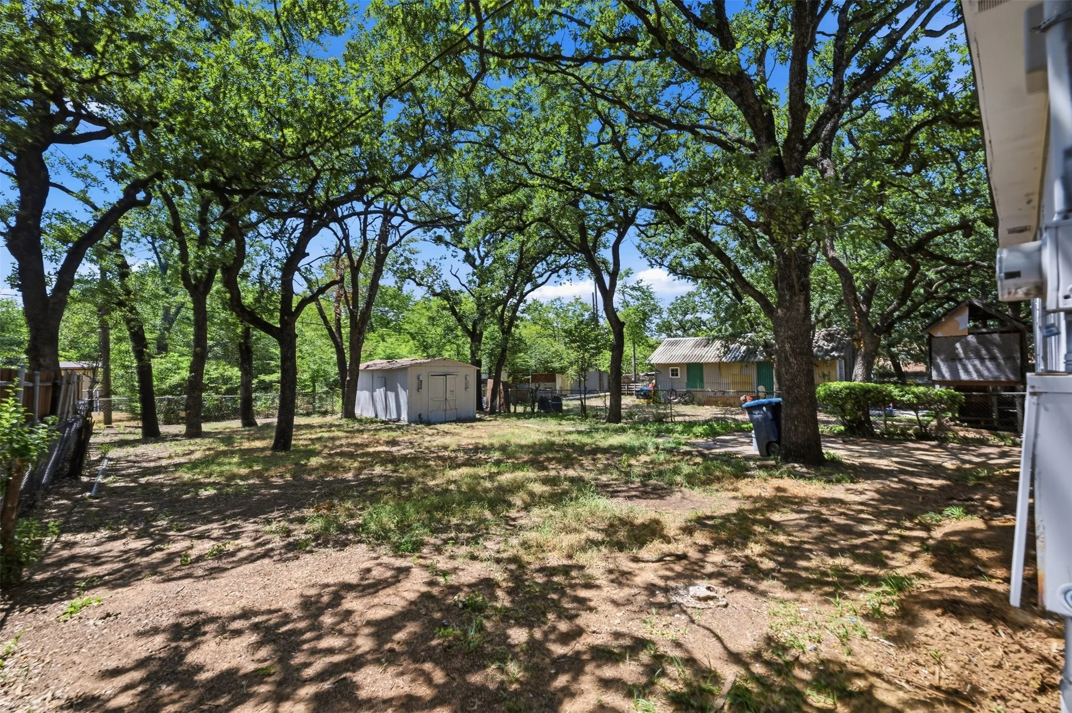 Expansive rear yard featuring numerous mature trees providing ample shade
