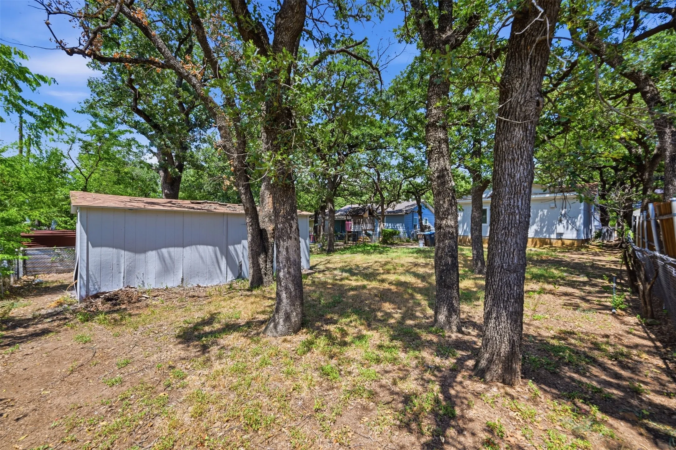 Expansive natural landscape featuring multiple mature trees and partial fencing