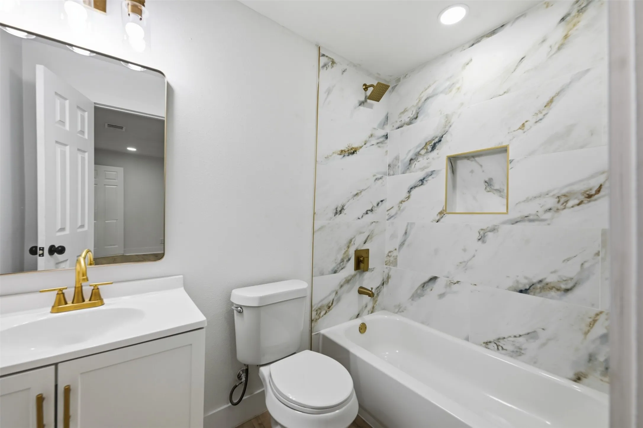 Bathroom featuring a white vanity with a single basin sink, gold-finish faucet, and coordinating cabinet hardware