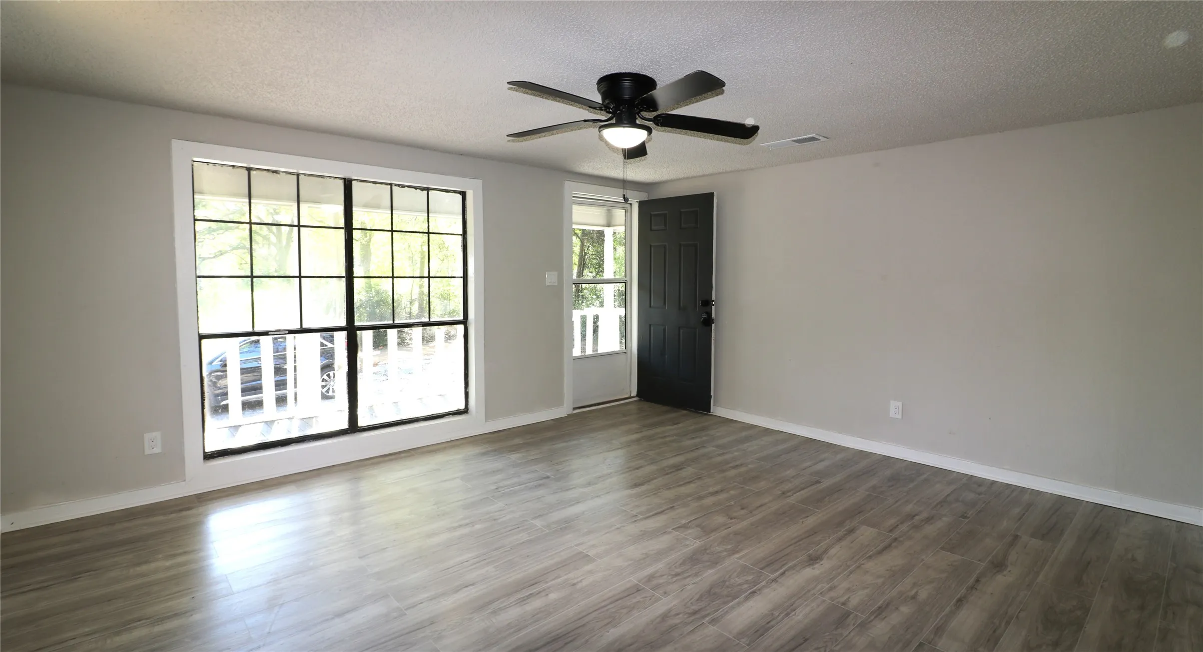 Empty room featuring a textured ceiling, a ceiling fan, and wood finished floors