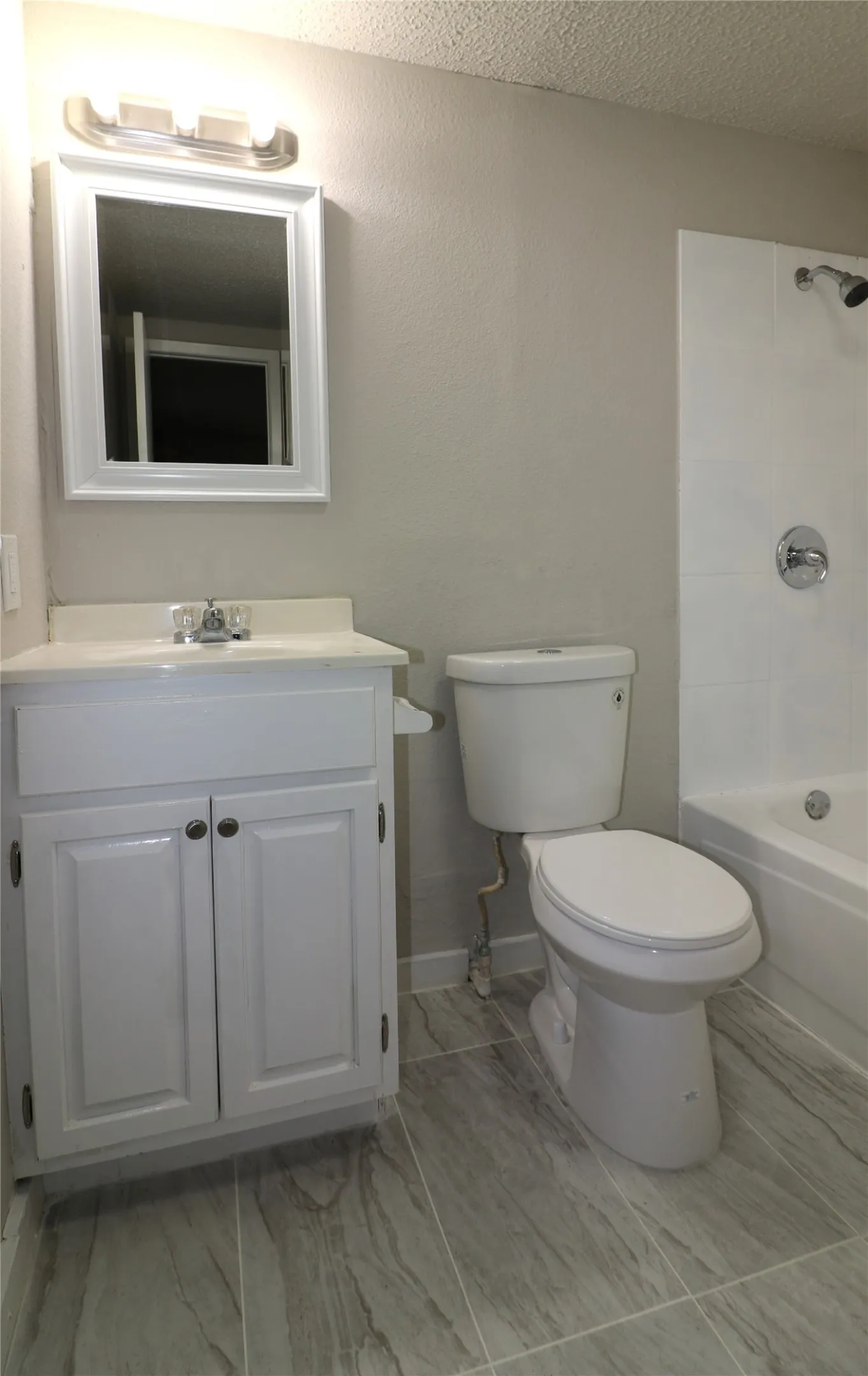 Full bathroom featuring vanity,  shower combination, and a textured ceiling