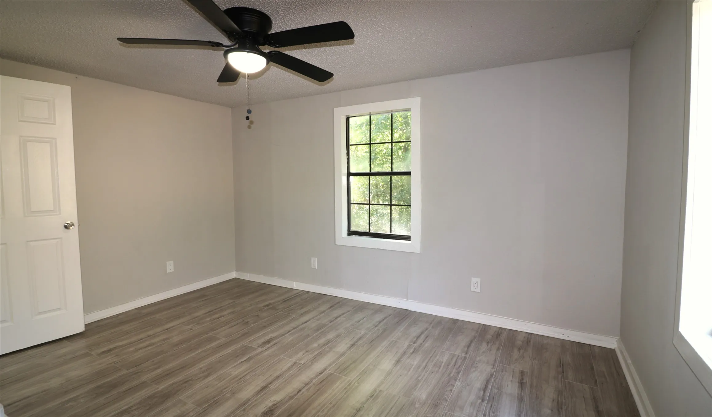 Unfurnished room featuring wood finished floors, a textured ceiling, and a ceiling fan