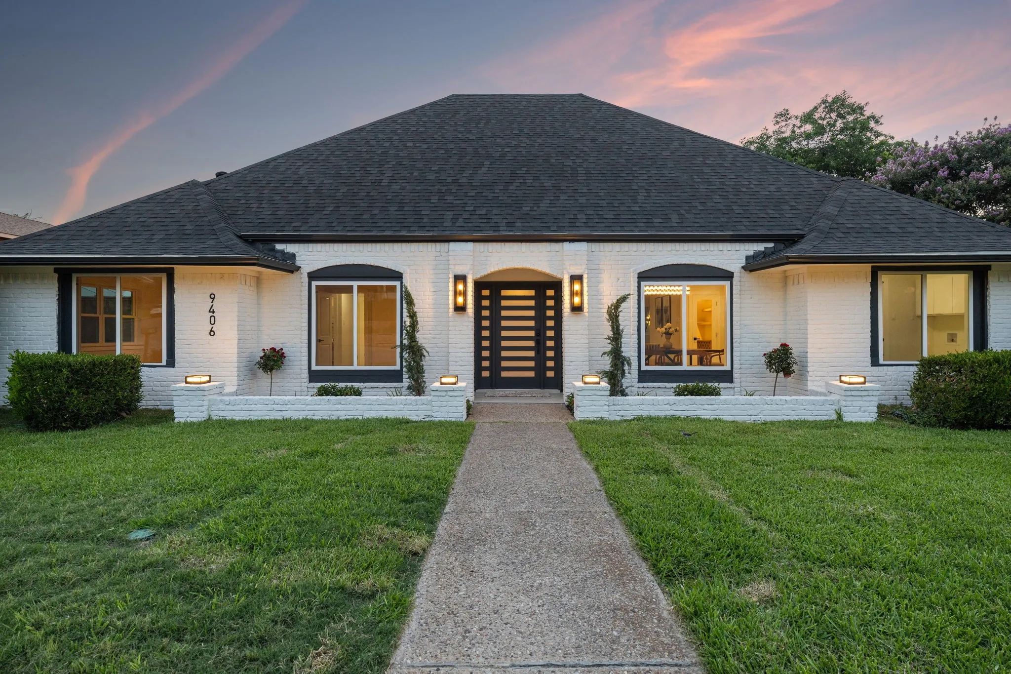 Single-story residence featuring a dark asphalt shingle roof and white painted brick exterior