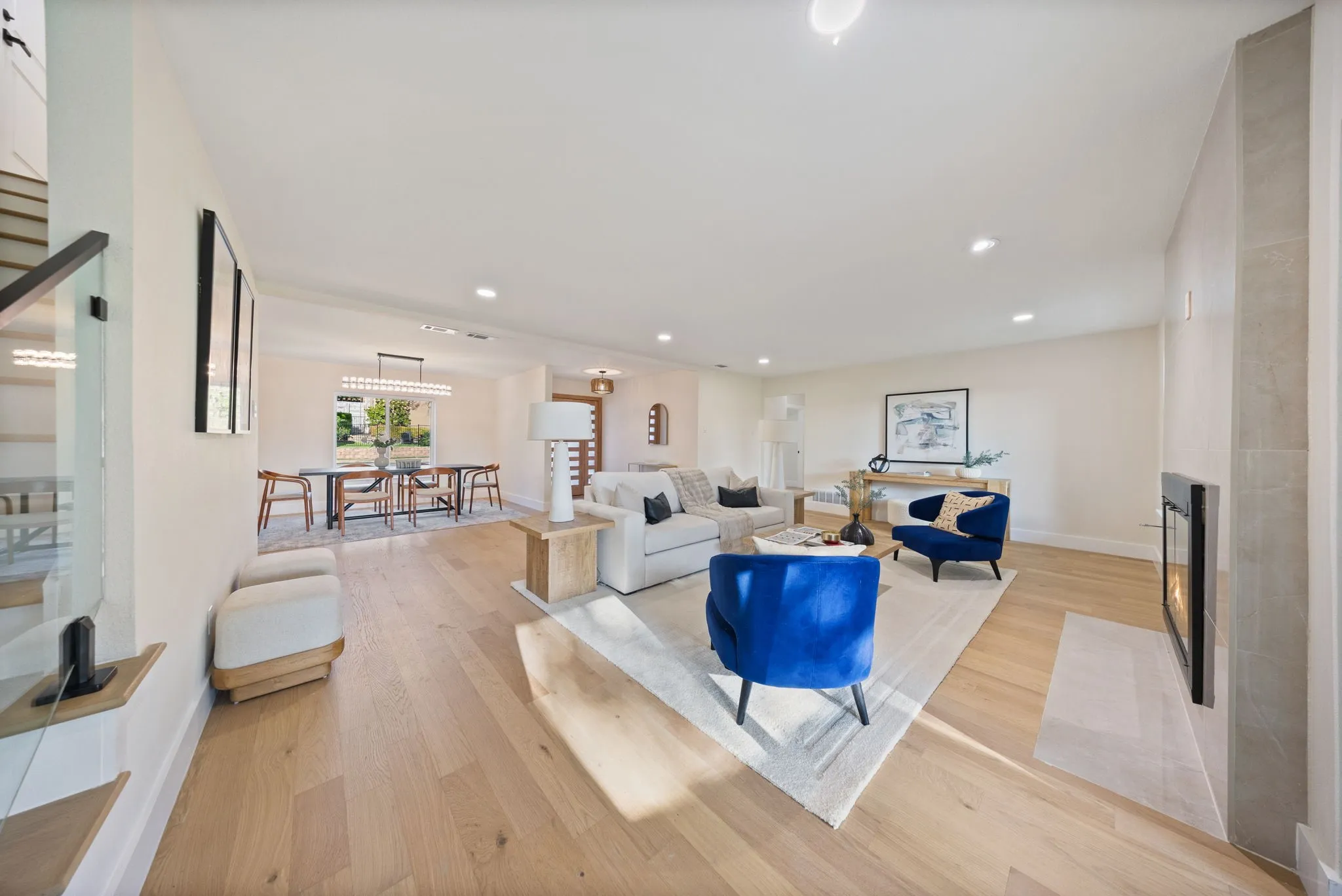 Spacious living area featuring light wood-finish flooring, recessed lighting, and a modern fireplace with a tiled surround
