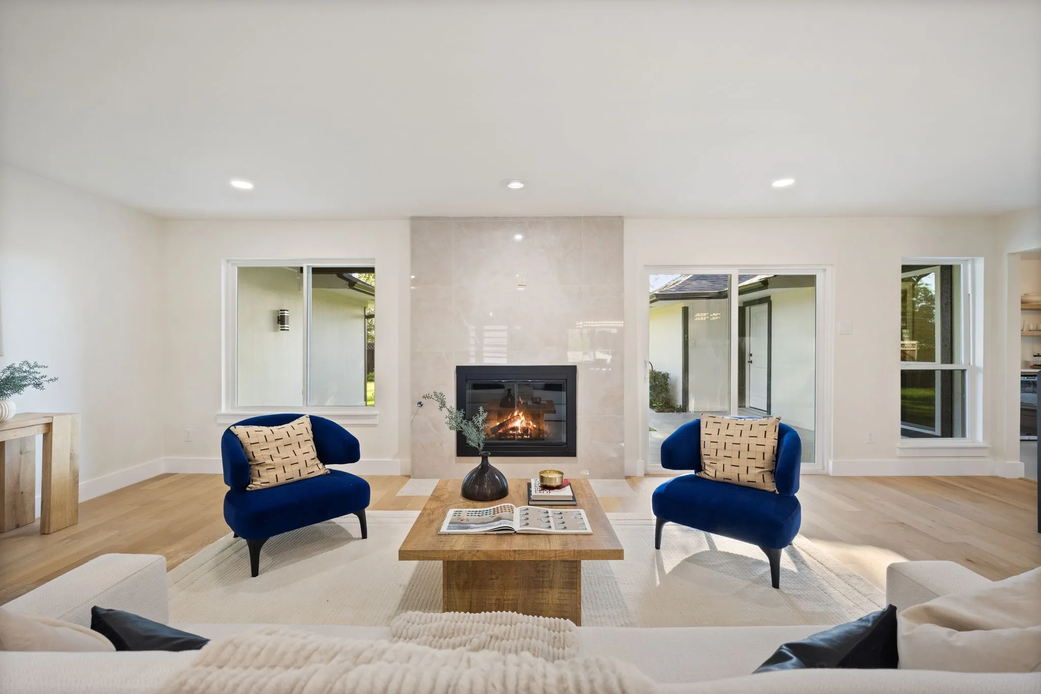 Living area featuring a modern fireplace with a light-toned tile surround, recessed lighting, wood-finish flooring, and sliding glass doors opening to the exterior