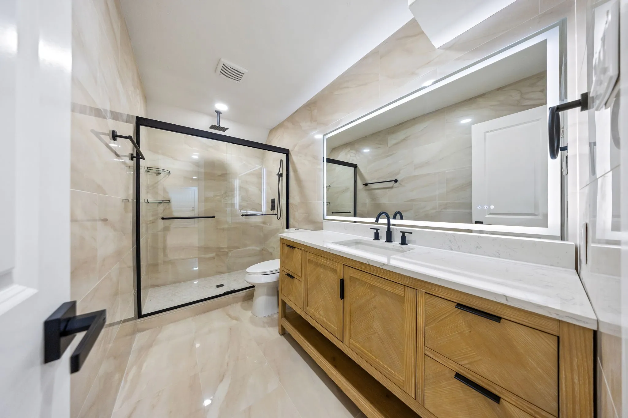 Bathroom featuring a floating wood-finish vanity with a white countertop and a frameless illuminated mirror