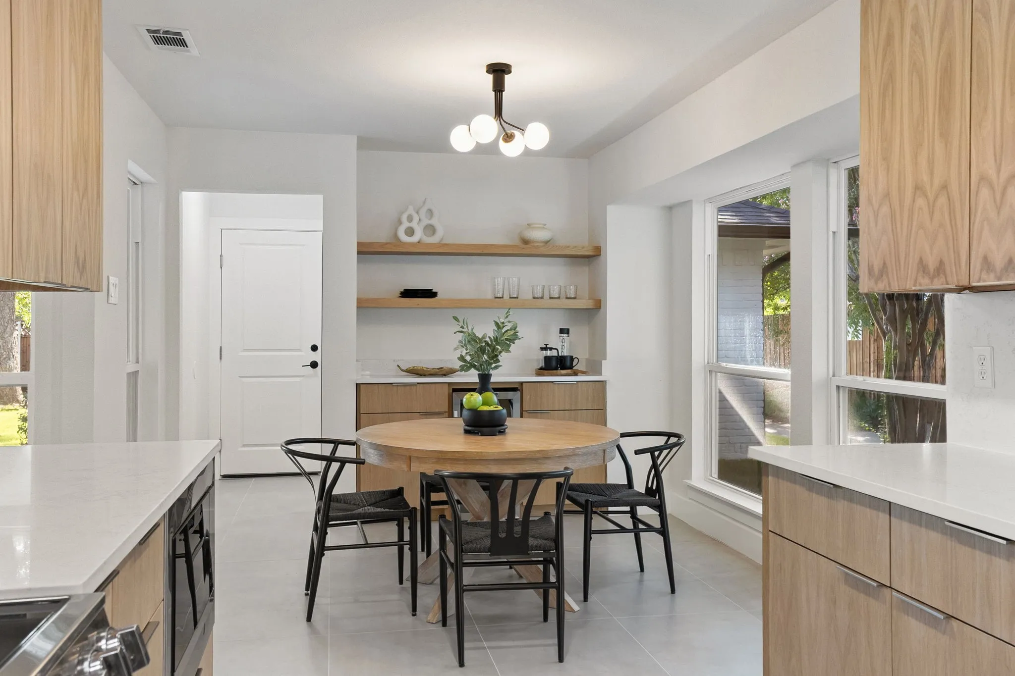 Modern kitchen featuring light wood-finish cabinetry, light-toned countertops, and a built-in beverage center