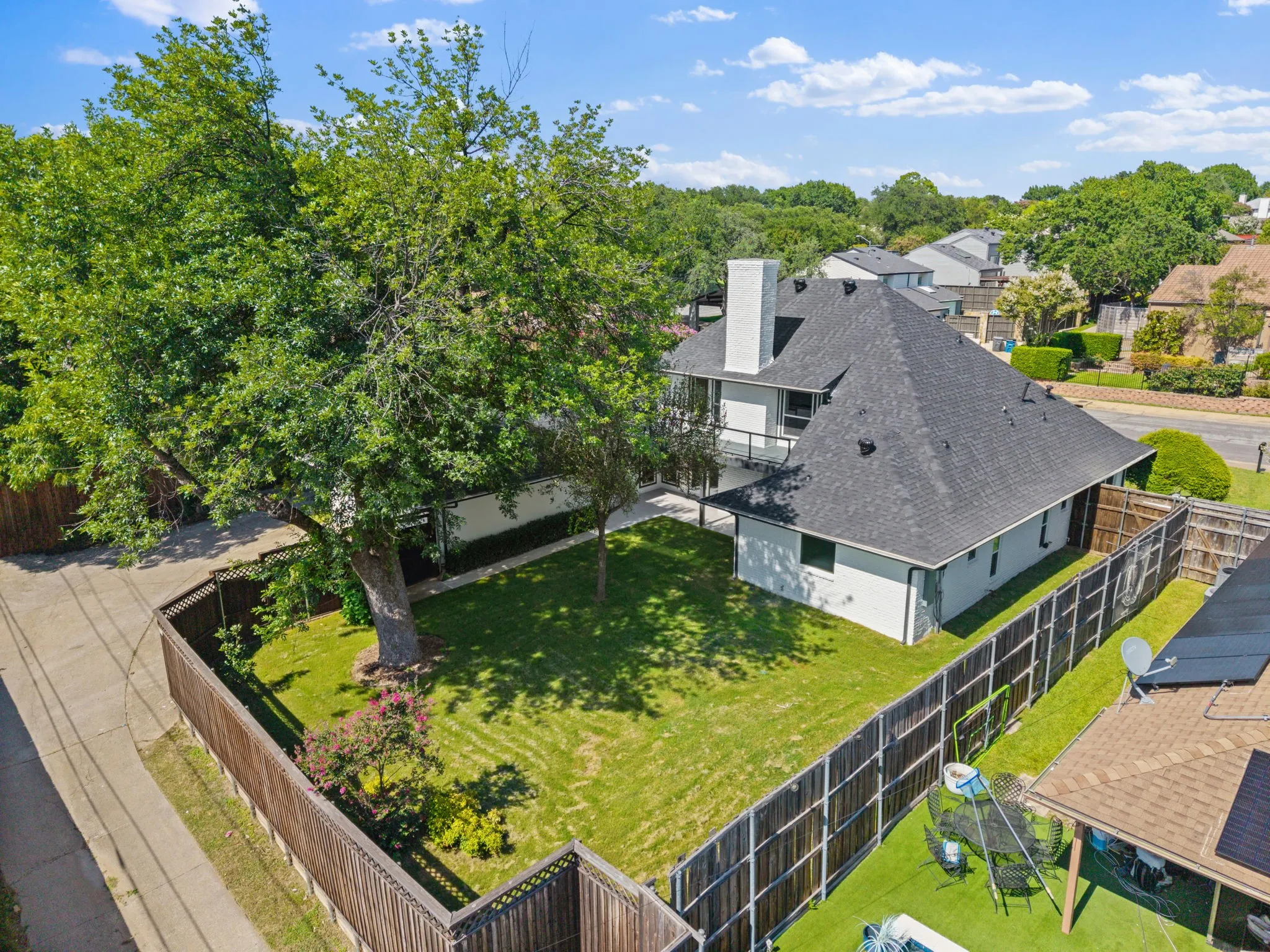 Expansive backyard featuring a large mature tree, manicured lawn, and wood privacy fencing