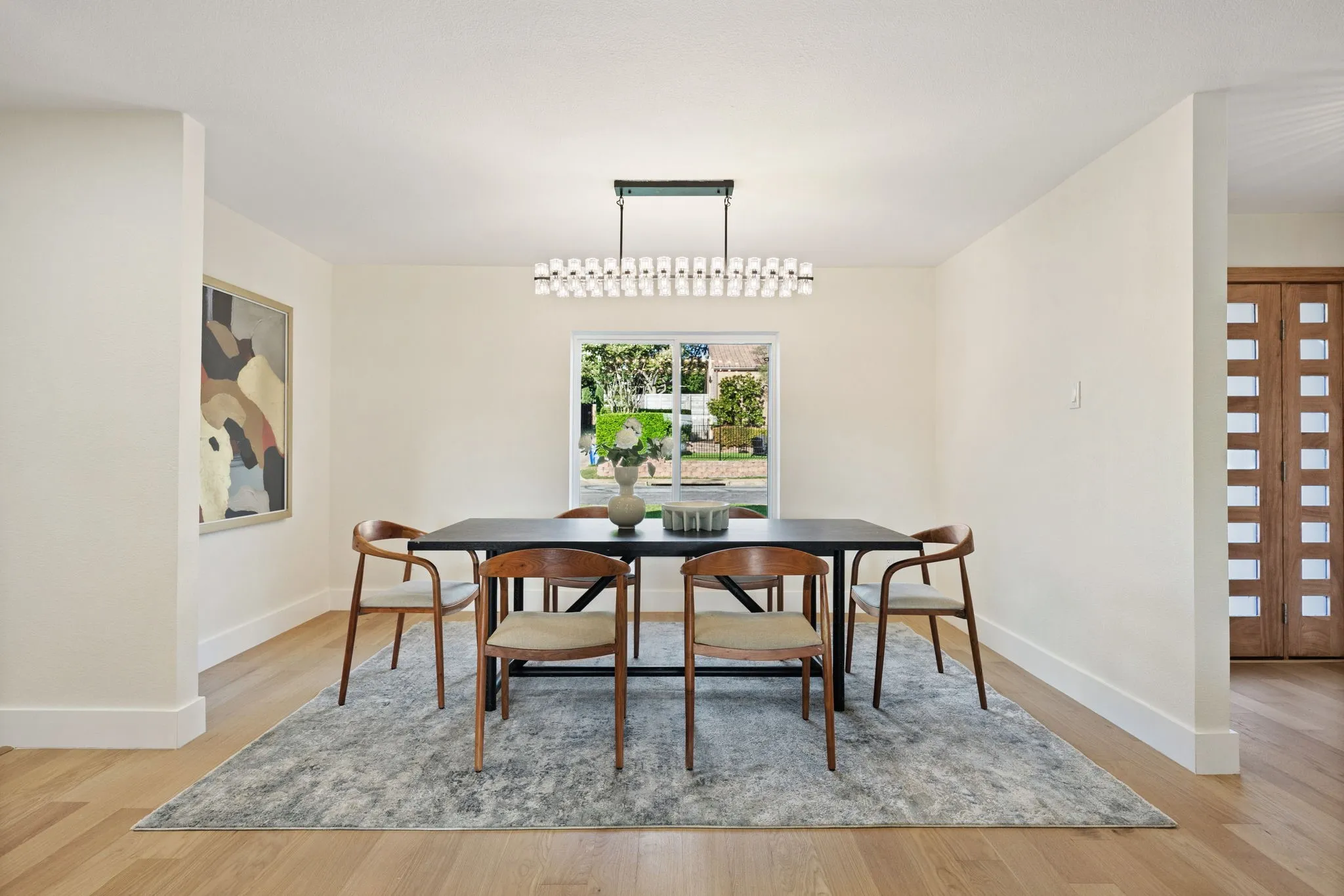 Dining area featuring light wood-finish flooring, a contemporary chandelier, a window with exterior views, and a paneled entry door