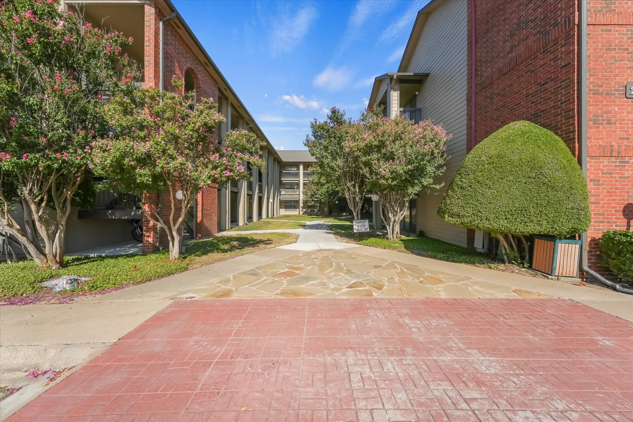 Brick exterior with balconies and mature flowering trees