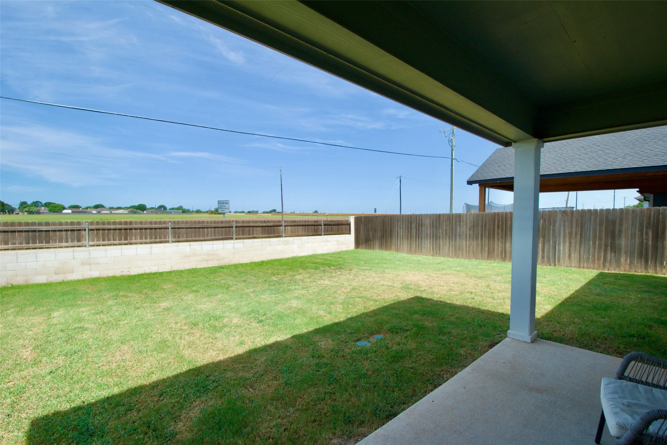 Expansive backyard featuring a manicured lawn, a solid wood privacy fence, and a concrete block retaining​​‌​​​​‌​​‌‌​‌‌​​​‌‌​‌​‌​‌​​​‌​​ wall