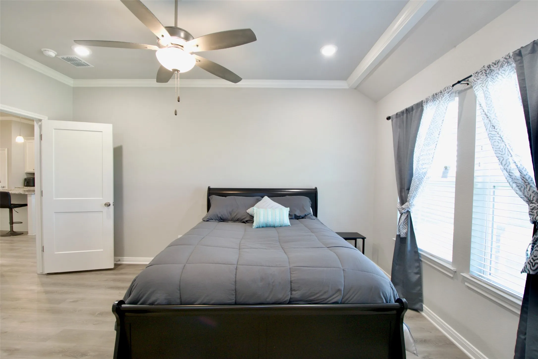 Wood-finish flooring throughout, tray ceiling with recessed lighting, and a ceiling fan with integrated light fixture