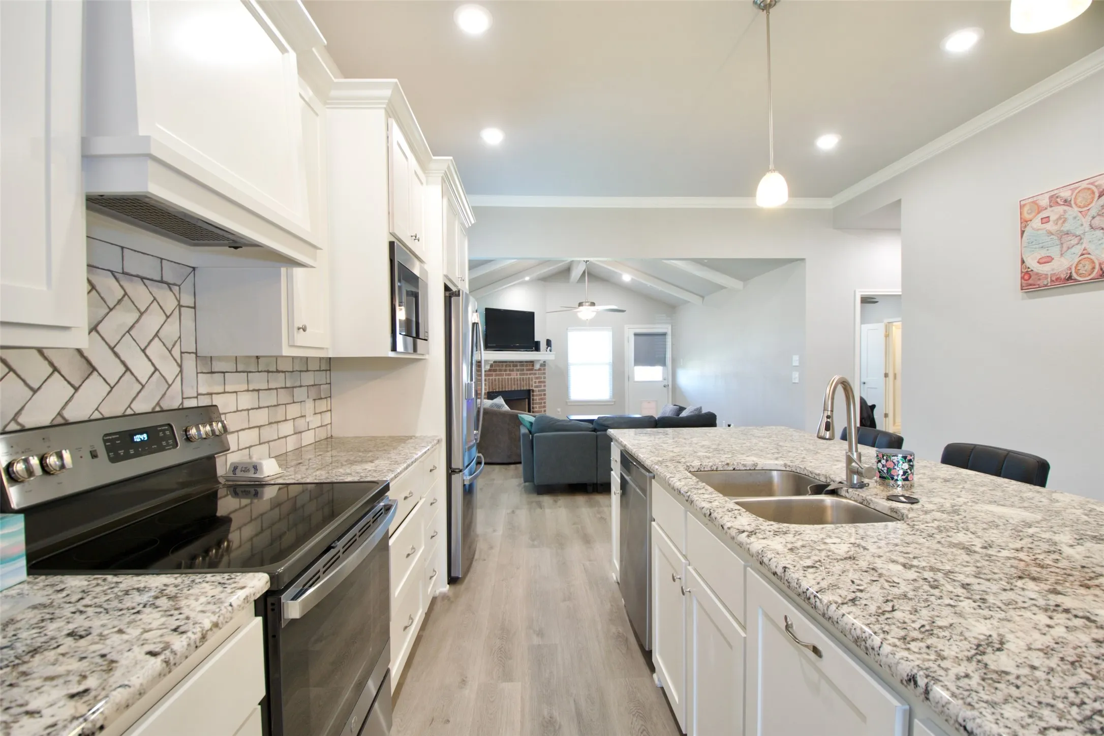 Kitchen featuring white cabinetry, light-toned countertops, a herringbone tile backsplash, stainless steel appliances, and wood-finish flooring