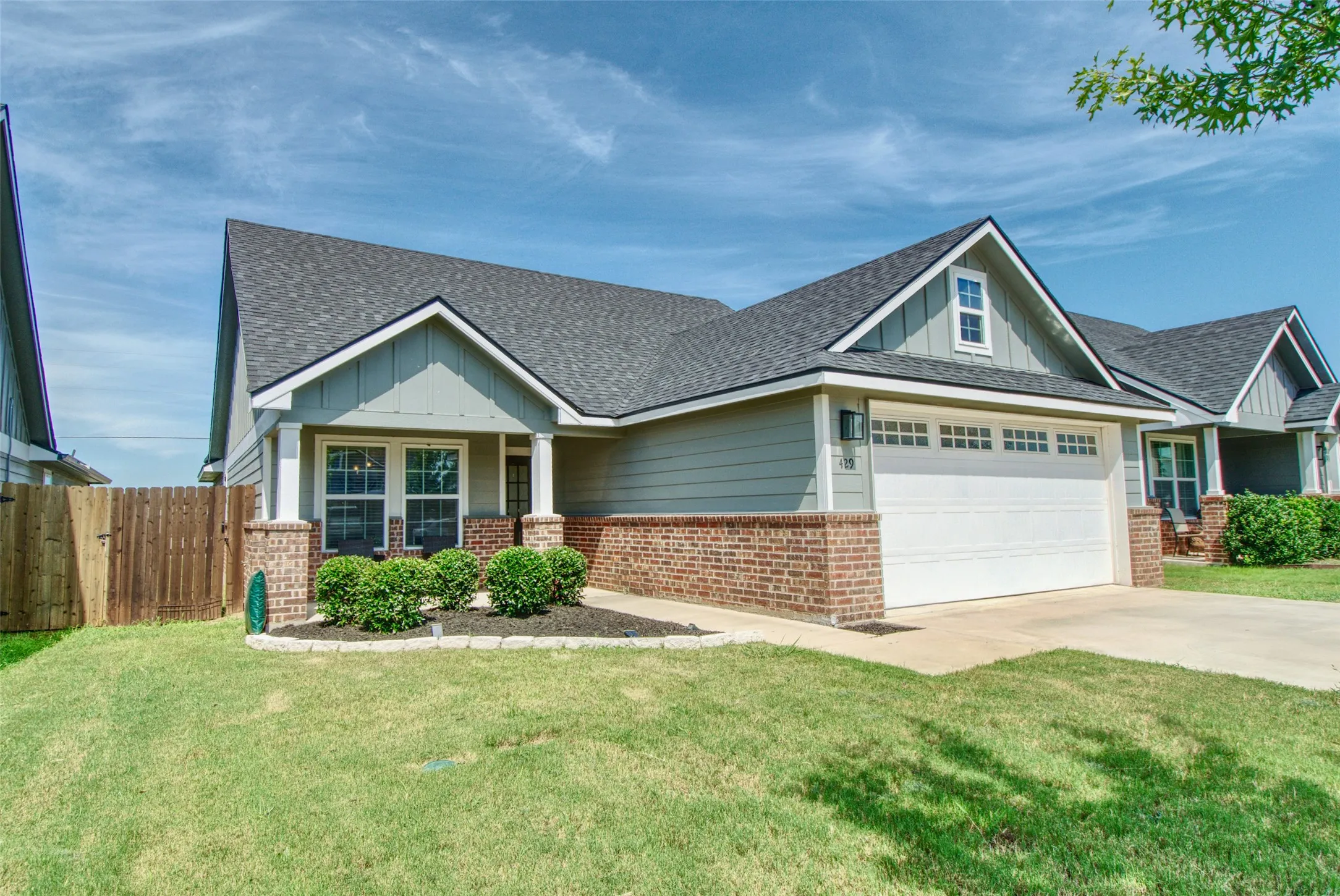 Contemporary suburban residence featuring light green siding and a dark shingle roof