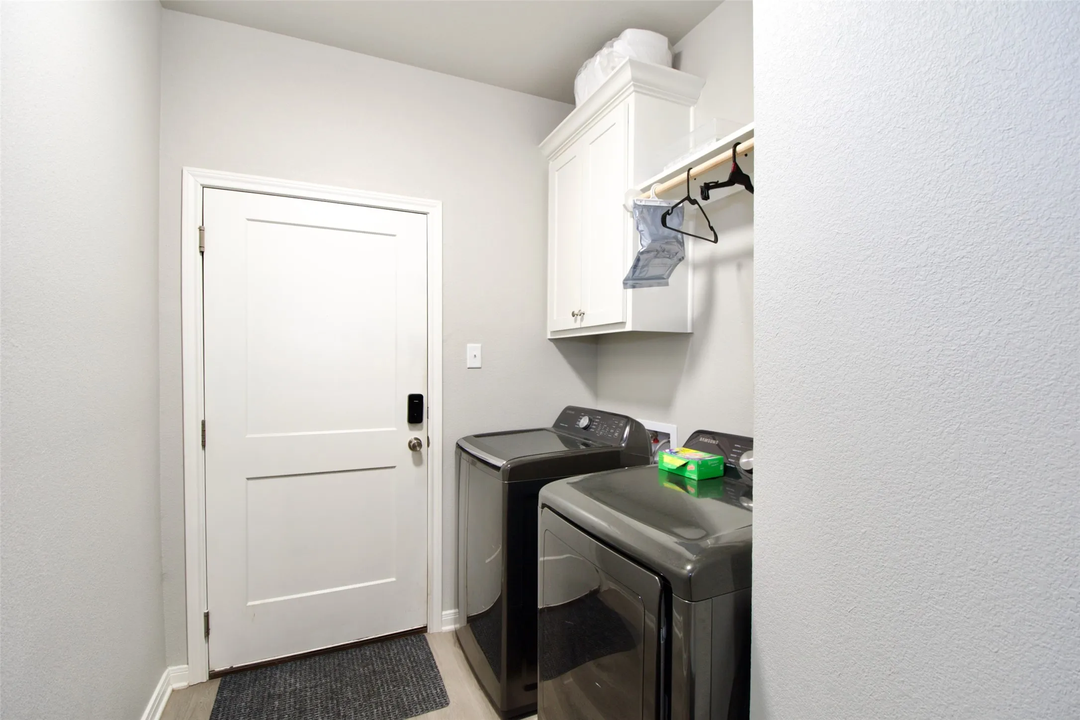 Dedicated laundry space featuring light grey walls, wood-finish flooring, and a white two-panel interior door