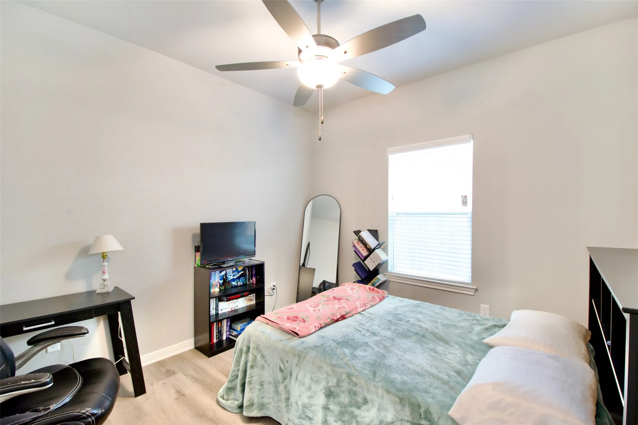 Interior room featuring light gray walls, wood-finish flooring, and a single window with blinds
