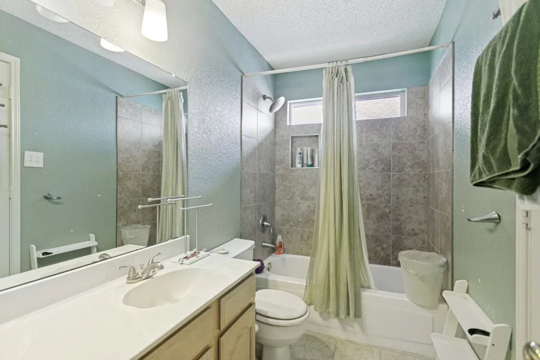 Bathroom featuring a white vanity with integrated sink, brushed nickel faucet, large wall mirror, and a tiled shower/tub combination with built-in niche and transom windows