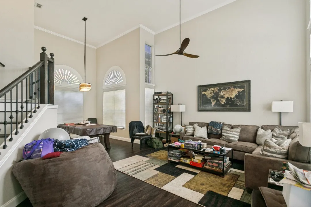 Two-story living area featuring a dark wood-finish staircase with wrought iron balusters, vaulted ceilings, arched transom windows, and dark wood-finish flooring
